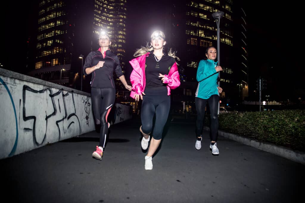 Three women running in the night in the city center