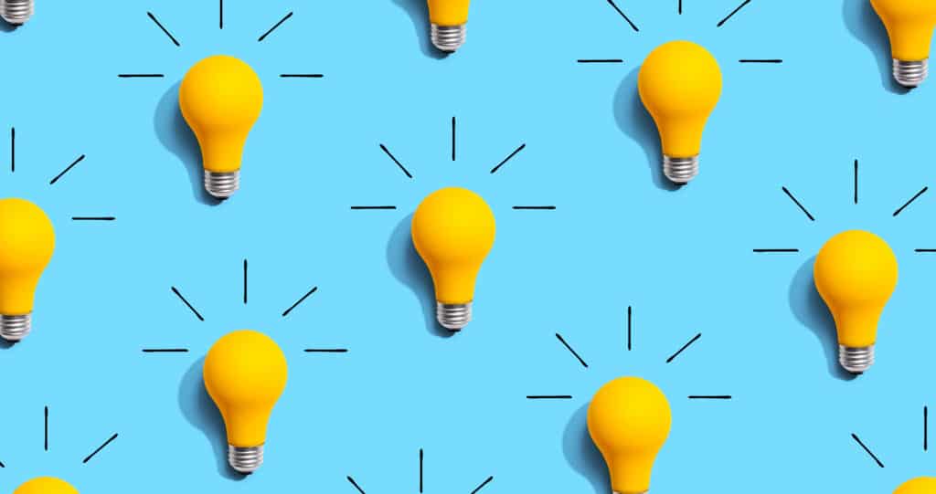 Pattern of yellow light bulbs on a blue background. Black lines surround each bulb, suggesting they are lit. The bulbs are evenly spaced, creating a symmetrical design that subtly draws on marketing psychology principles to grab consumer attention and influence behavior.