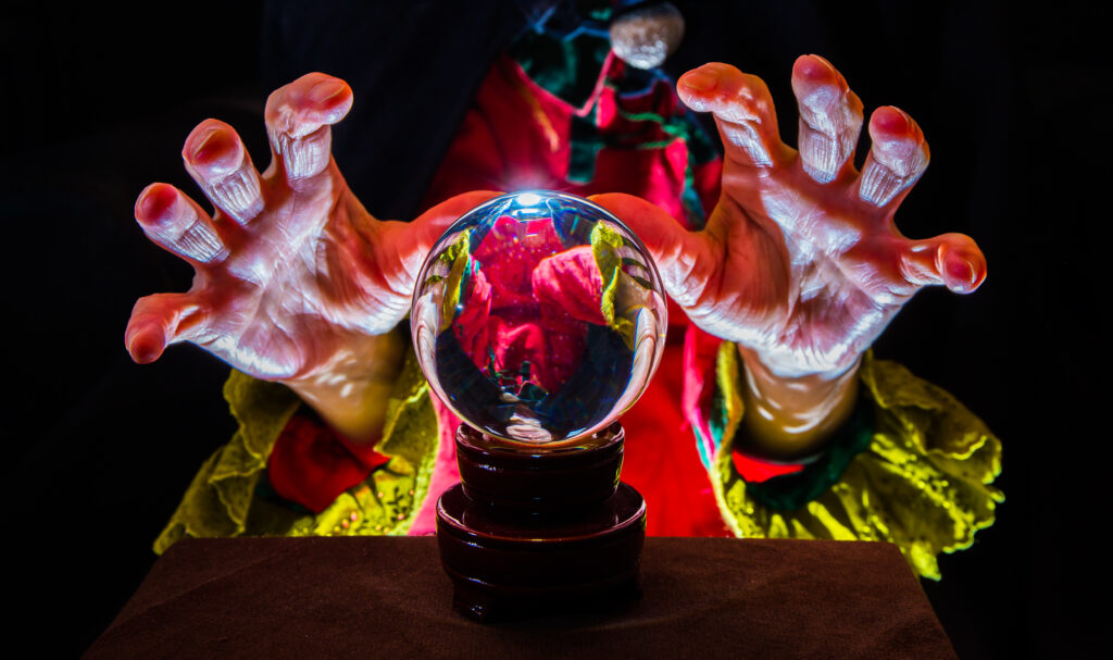 A pair of hands with exaggerated gestures hover over a glowing crystal ball, as if predicting the mysterious trends in consumer behavior. The dimly lit background accentuates the colorful, textured sleeves, enhancing the enigmatic atmosphere.