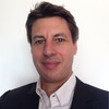 Man with short, dark hair wearing a white shirt and black blazer, standing against a plain white background. His confident stance reflects a deep understanding of marketing psychology, ready to unravel the intricacies of consumer behavior.